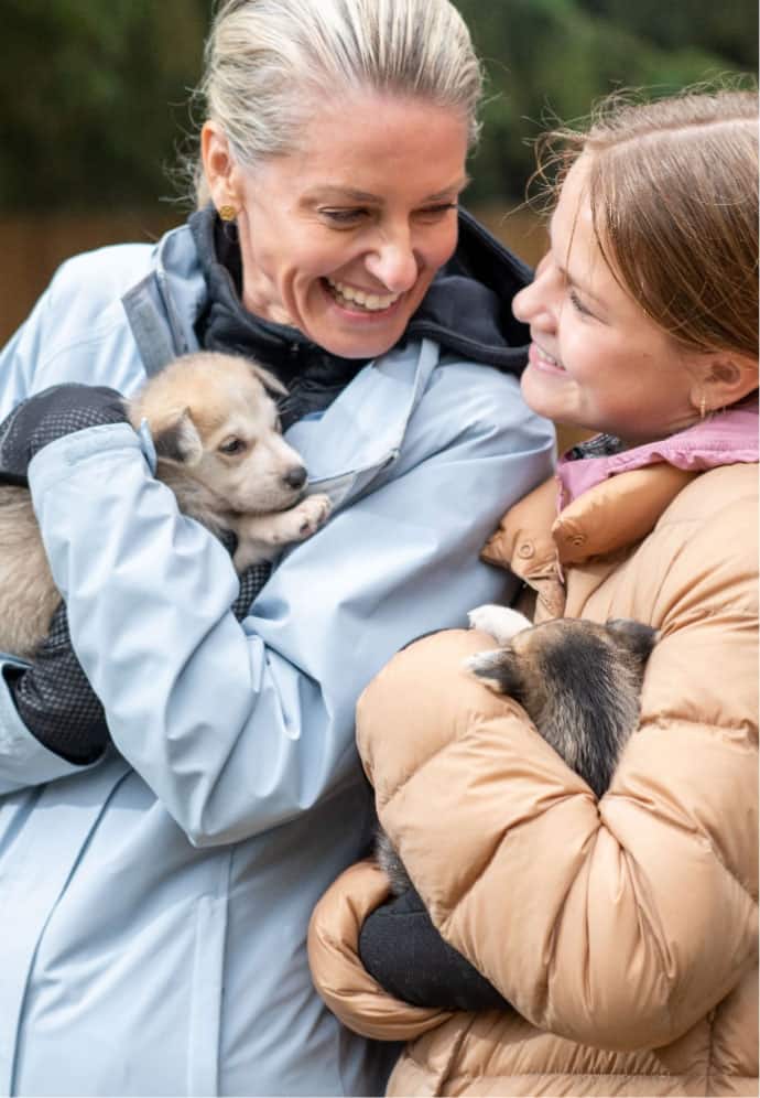 Mother and daughter playing with Husky puppies on an Alaska Shore Excursion