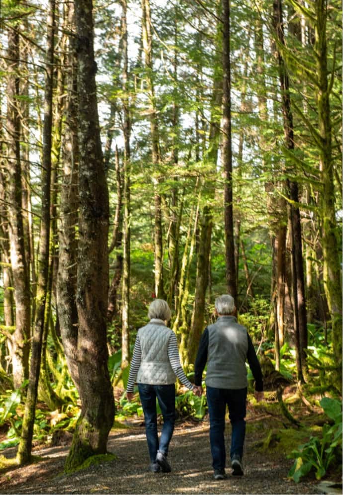 A couple walks along a trail path in the Alaskan forest near Ketchikan, Alaska