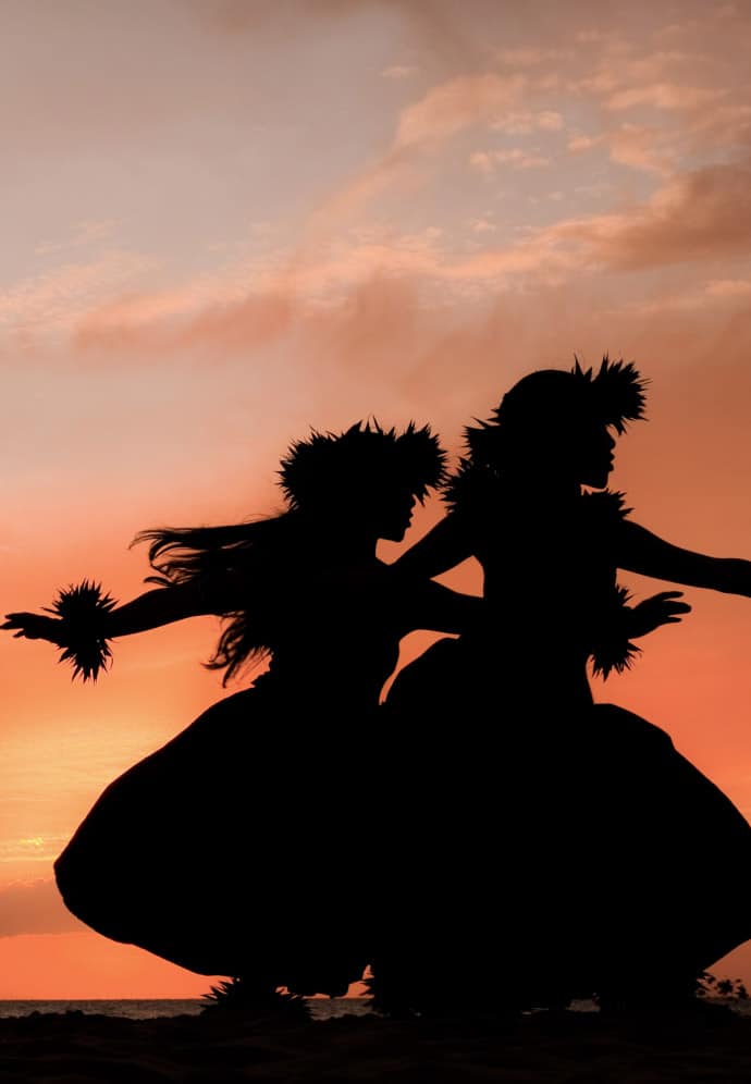 hula dancers preforming in silhouette in front of a Hawaiian sunset