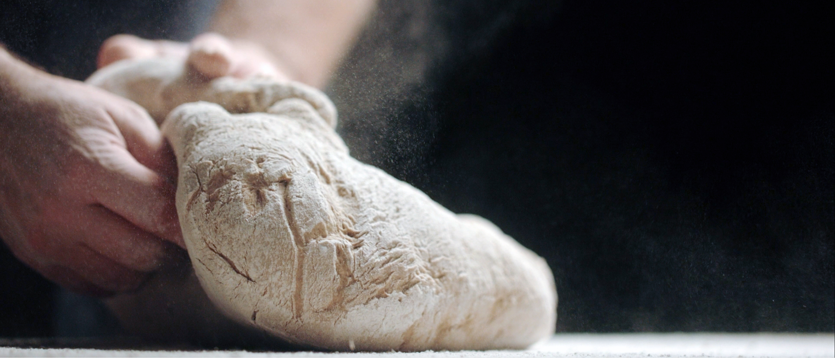 Two hands kneading bread dough.