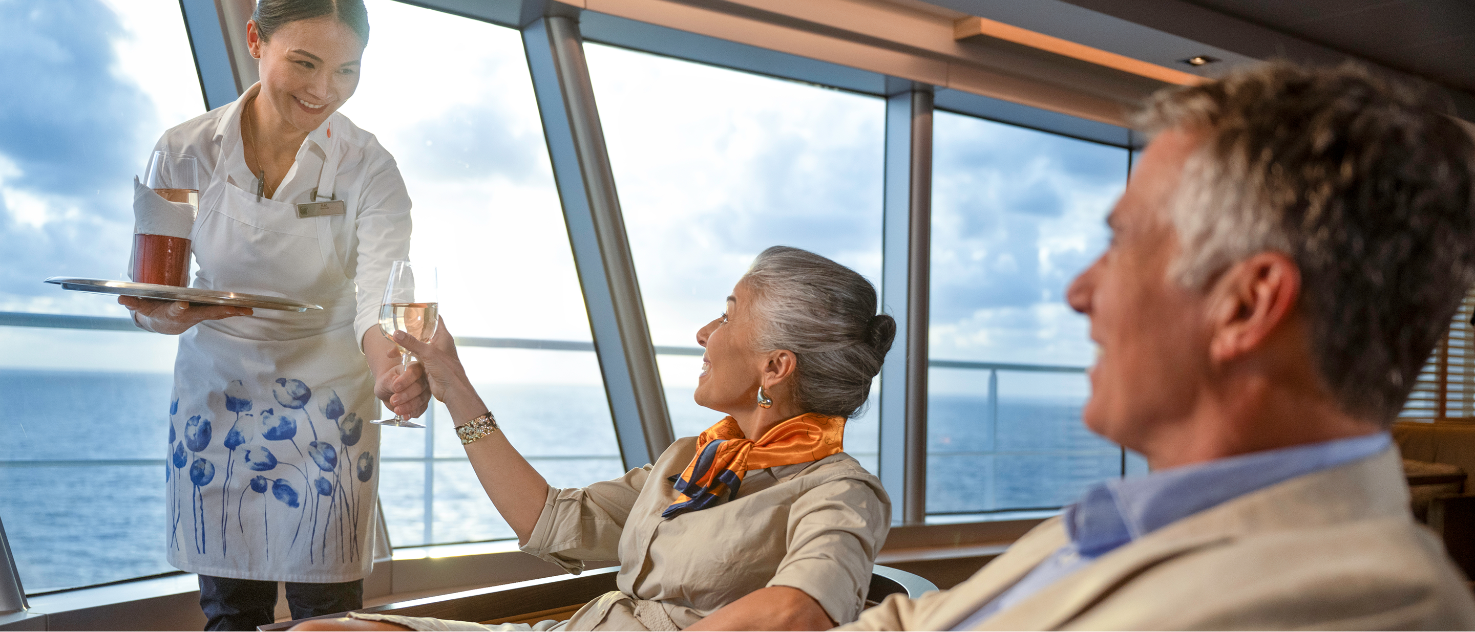Ship crew member offering drinks to guests.