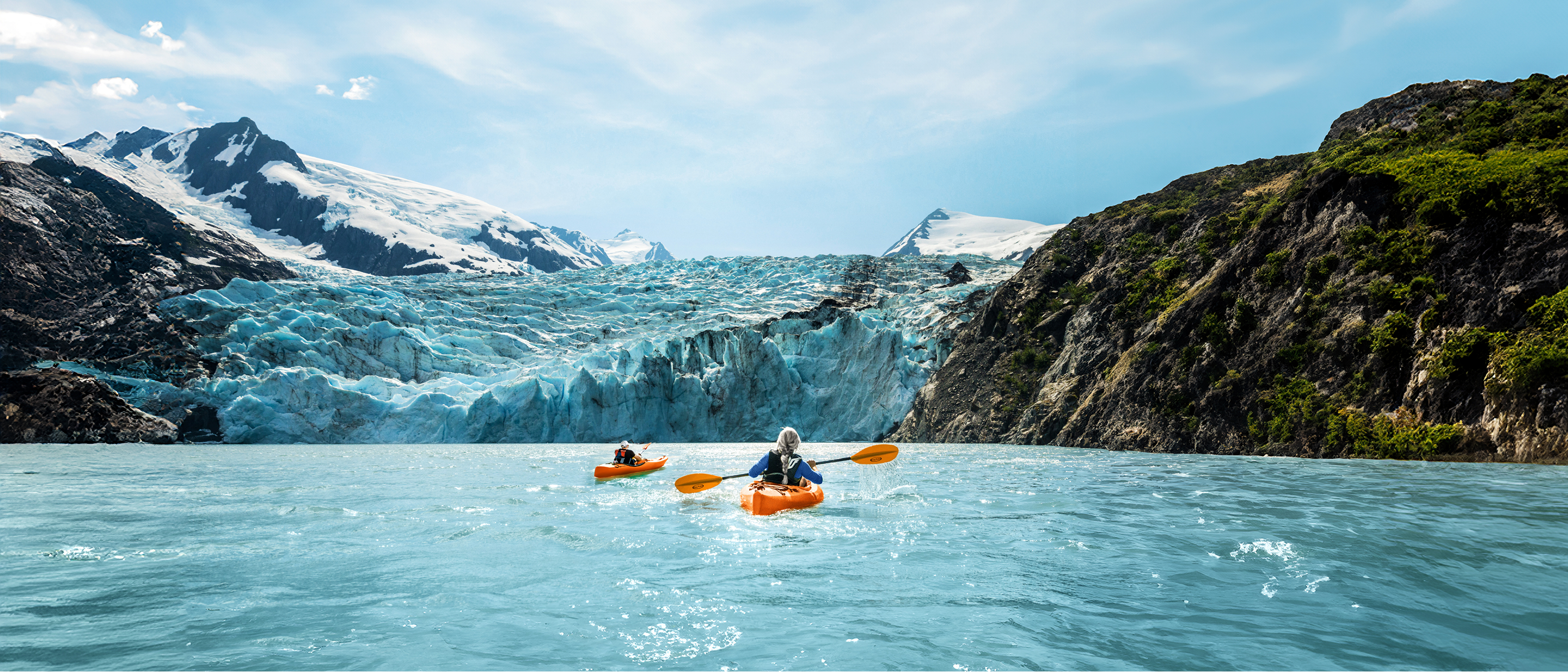 Two persons kayaking in a glacial lake.