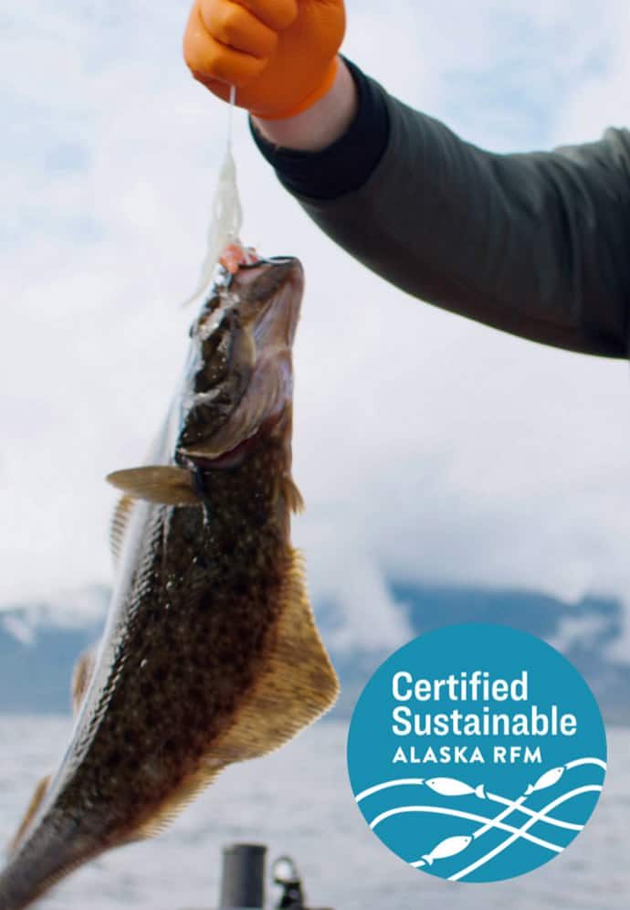 Image of a man holding up a freshly caught fish with an emblem stating Certified Sustainable, Alaska RFM.